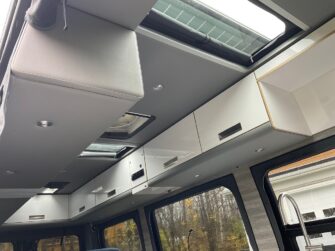 Au plafond, beaucoup d’armoires de rangement, mais aussi trois lanterneaux pour maximiser la lumière à l’intérieur. - Magazine Camper